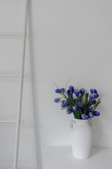 Elegant decorative wooden ladder with artificial blue crocus in vase in minimal style. Clean, uncluttered design featuring artificial flowers, vases, and a staircase.