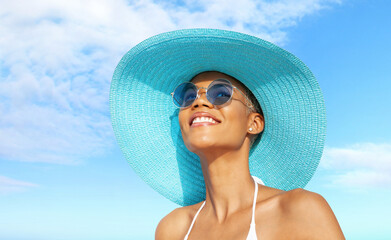 Happy young woman at the beach side, wearing a turquoise sun hat, blue sunglasses and bikini,...