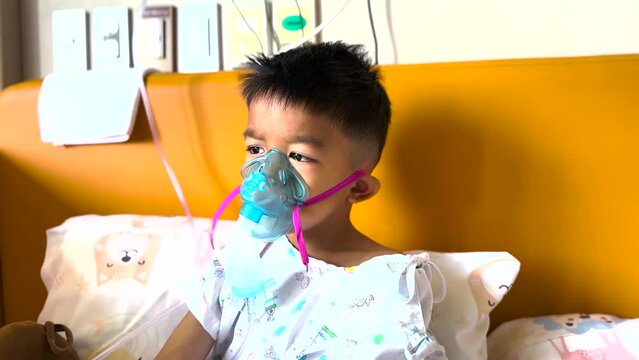 Asian little kind boy is patient by inhalation therapy  with oxygen mask breathes through nebulizer at hospital. kid with RSV ,Respiratory Syncytial Virus, problem