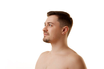 Profile view of half-naked man looking away with light smile against white studio background....