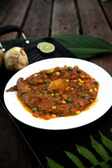 Vertical shot of a bowl of stew with peas and corn on a wooden table