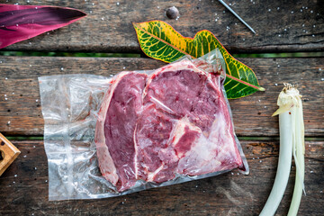 Top view of a raw red steak in a plastic bag on a picnic table