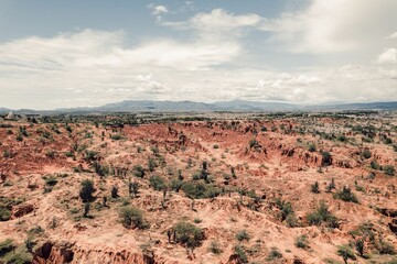 Beautiful view of a rocky desert with trees under a cloudy sky.
