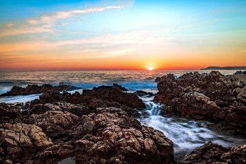 Beautiful view of a rocky shore under the blue sky during sunset