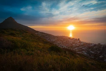Fotobehang Gorgeous view of a mountainside town in Africa overlooking the calm sea at sunrise © Wirestock