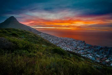 Fotobehang Gorgeous view of a mountainside town in Africa overlooking the calm sea at sunset © Wirestock