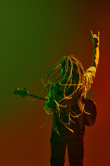 Rock and roll energy. Young guy, musician with dreadlock playing guitar and showing rock and roll...