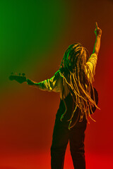 Lost ion the music. Back view of musician with dreadlock playing electric guitar, performing solo...