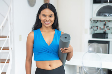 Beautiful latin american woman with yoga mat ready for class at gym