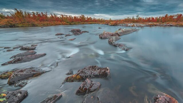 A shallow river with forest-covered banks flows through Finning tundra. A timelapse video.