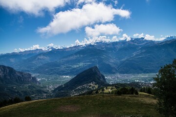Aerial shot of a rock and a town in the distance in summer in Valais, Switzerland