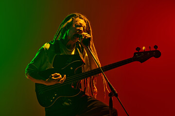 Creating energy. Artistic young man with dreadlock, musician singing and playing electric guitar...