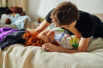 loving appealing girlfriend and boyfriend preparing to kiss alluringly while lying on their bed - obrazy, fototapety, plakaty