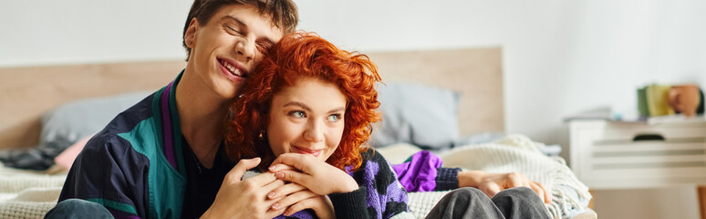 stylish jolly girlfriend and boyfriend in cozy outfits hugging each other while at home, banner - obrazy, fototapety, plakaty