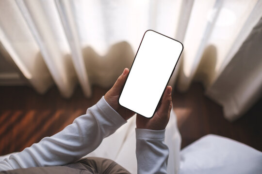 Top view mockup image of a woman holding mobile phone with blank desktop white screen