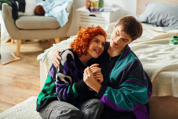 beautiful red haired woman and her handsome boyfriend having good time and hugging lovingly - obrazy, fototapety, plakaty