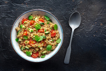 Quinoa tabbouleh salad in a bowl, a healthy dinner with tomatoes and mint, top shot with copy space