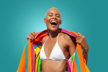 Happy laughing woman wrapped in a colorful towel, African latin American woman isolated on blue background. Concept of summer beach holiday or booking travel and resort accommodations or for shopping