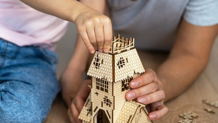 Close up of childrens and fathers hands build wooden details of construction set. Construction kit....