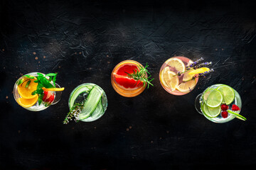 Fancy cocktails with fresh fruit. Gin and tonic drinks with ice at a party, on a black background, overhead flat lay shot