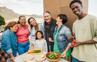 Happy multiracial family preparing sunday lunch at home rooftop - Multigenerational people having...
