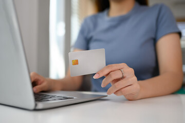 Close up woman holding credit card making payment on laptop computer