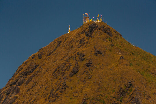 A mountain with a brown hillside and a blue sky