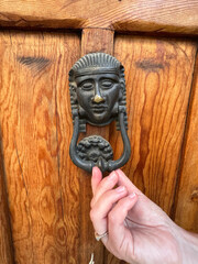 Decorative door knocker made of bronze in the form of a woman's head and a woman's hand holding it