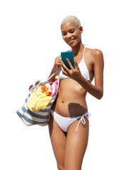 Happy woman at the beach side wearing bikini holding a beach bag and using mobile phone, isolated on white background. Concept of summer beach holiday, shopping online, booking travel and resort