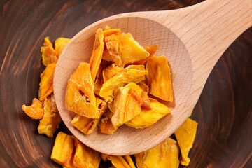 Dried organic mango slices in rustic kitchen dish with wooden spoon
