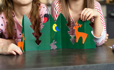 Close up of childrens hands make diy from colored paper. Girls with handmade craft animals in...