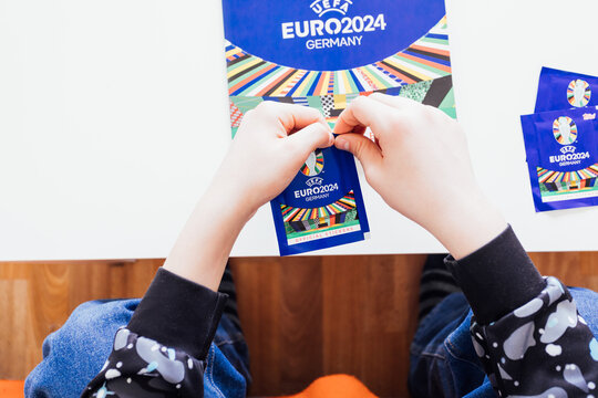 BERLIN, GERMANY - APR 6, 2024: Teenager boy with trading cards by Topps collectors sticker album for UEFA EURO football championship in 2024 taking place in Germany, Europe.