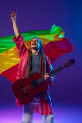 Energetic musician, man with striking dreadlocks playing guitar over red, yellow, and green flag...