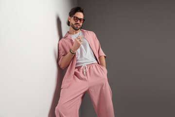 cool fashion man in pink clothes with sunglasses holding hand in pocket