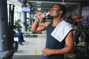 happy young african man drinking water after exercise