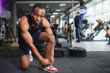 Fototapeta na wymiar African Man tying shoelaces at sneaker in the gym