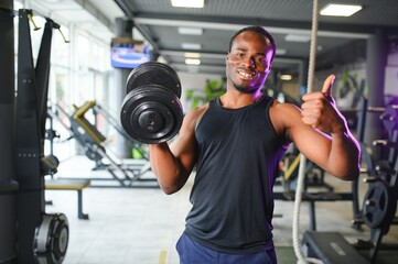Fototapeta na wymiar healthy african man working out with dumbbells in gym