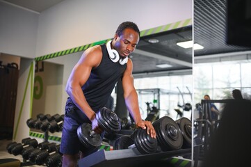 Black Male Athlete Taking Dumbbell From Rack At Gym