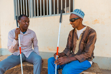 Two blind men sitting on a bench are having a conversation, friendship between people suffering...