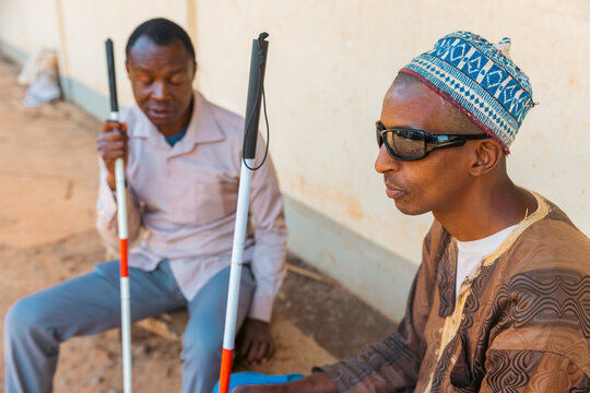 Two blind men sitting on a bench chatting, disabled people together