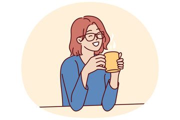 Joyful woman holding coffee mug sitting at table and smiling remembering happy moments from life during lunch break. Girl in casual clothes drinks hot tea or coffee to gain vigor and energy - obrazy, fototapety, plakaty