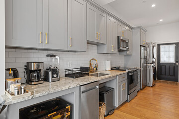 Modern grey kitchen cabinets with elegant gold hardware on doors and backs.