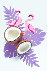Broken coconut, paper tropical leaves and flamingos on a white background.