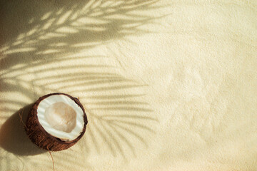 Broken coconut and shadow from palm leaves on the sand.