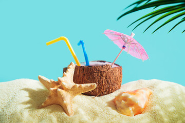 Coconut with a straw, shells, starfish and a sun umbrella on the sand. - 779665039