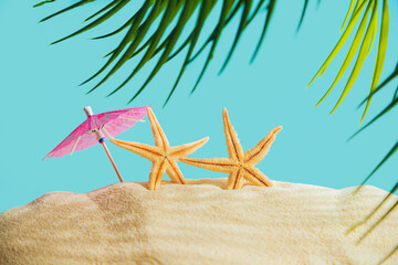Starfish with a sun umbrella and a palm tree on a sandy beach. - 779665063