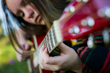 Close-up of a young woman's hands strumming the guitar. - 779665610
