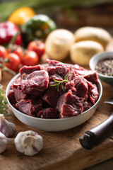 Pieces of chopped beef in a bowl with vegetables, ready for goulash