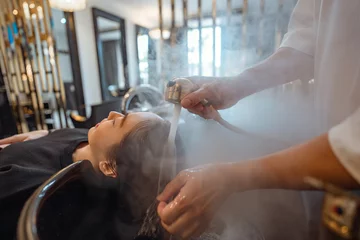 Foto auf Acrylglas Antireflex Hairdresser in beauty salon massage head customer and hair care in procedure of steaming water steam. Customer feeling relax while hairdresser massaging head at beauty barber shop © oatawa