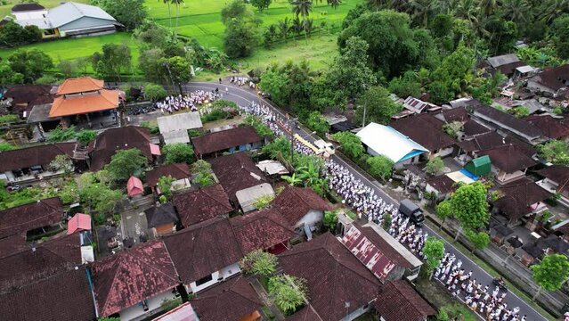 Large group of people wait at roadside to join ceremonial procession. Aerial view. Village residents wearing white clothes, carry offerings and go together to the beach, Melis day event